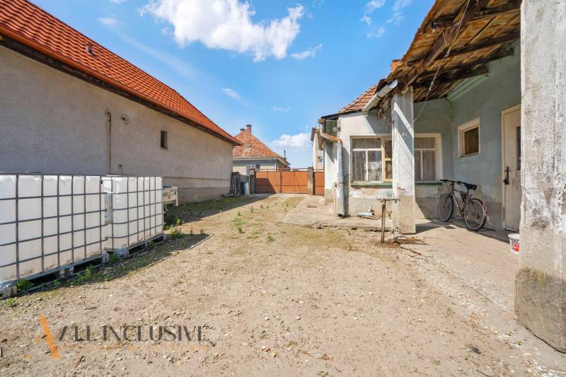 NA PREDAJ 4-IZBOVÝ RODINNÝ DOM V JAHODNEJ - Dvor rodinného domu v Jahodnej s bicyklom a veľkými nádržami na vodu.