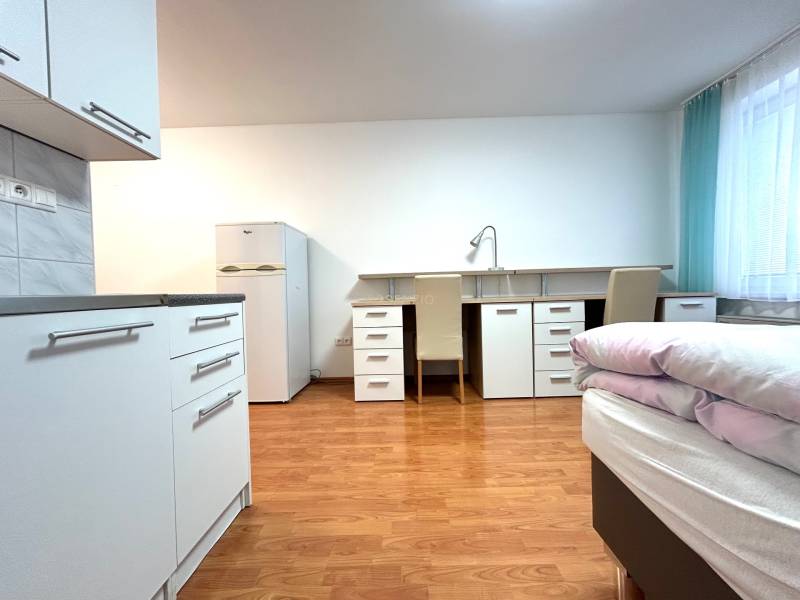 PREDAJ-GARSÓNKA-20m2-GUOTHOVA- KRAMÁRE - Garsónka so svetlým interiérom, kuchynským kútom, stolom, dvomi stoličkami a lôžkom.