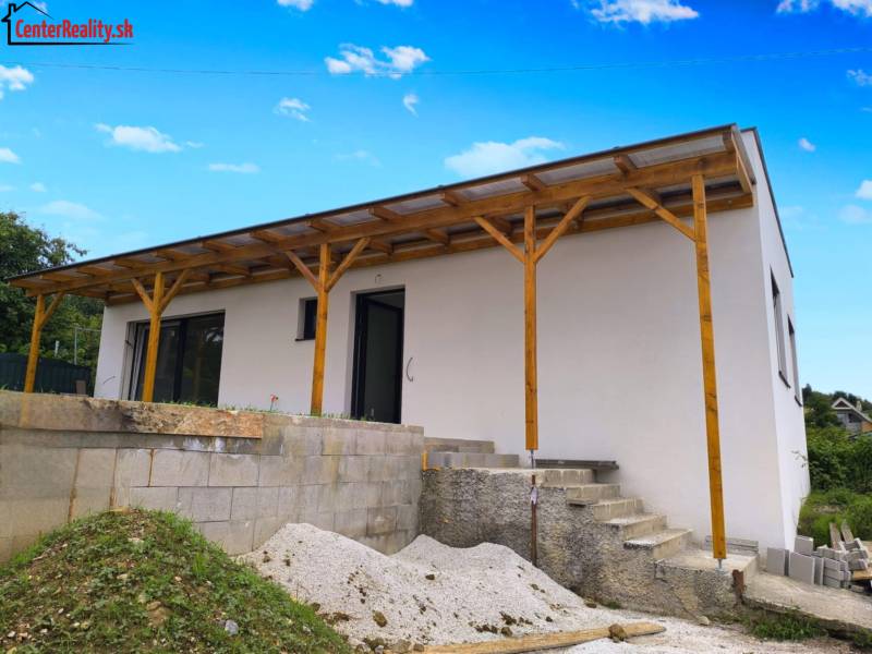 ‼️ NOVO POSTAVENÝ RODINNÝ DOM  S GARÁŽOU NA PREDAJ, MALÉ KRŠTEŇANY  ‼️ - Rodinný dom v Malých Krštenanoch má bielu fasádu a drevený prístrešok.