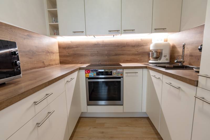 Jedinečný 3-izbový apartmán s balkónom, 71 m², Nový Ružinov - Kuchyňa v 3-izbovom byte: biele skrinky, drevená pracovná doska, spotrebiče.