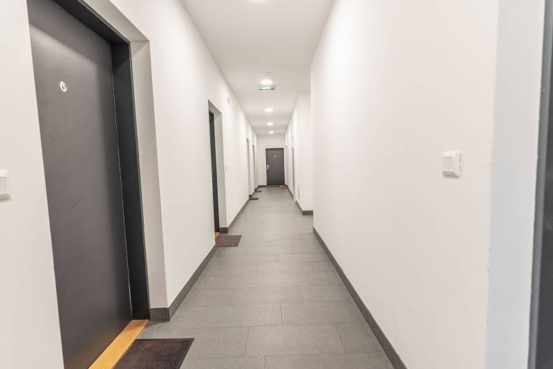 Jedinečný 3-izbový apartmán s balkónom, 71 m², Nový Ružinov - Chodba v bytovom dome s viacerými tmavými dverami.