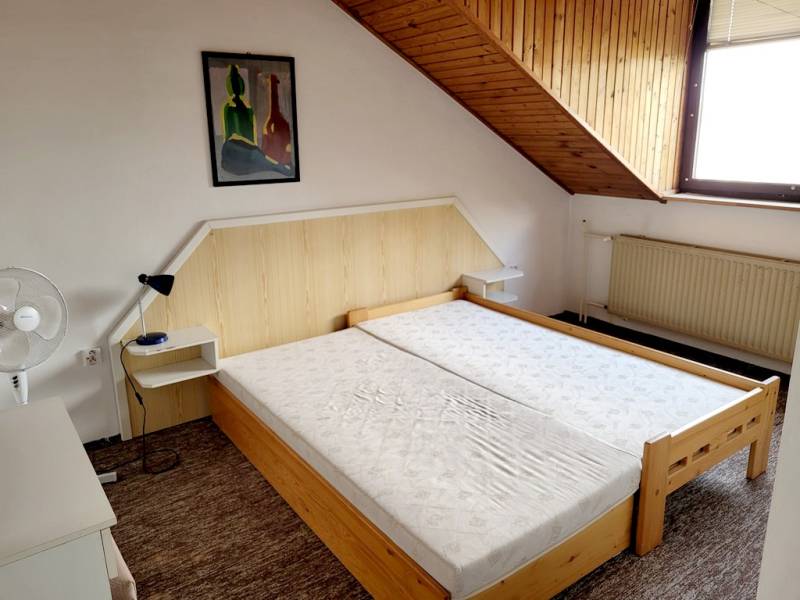 Na prenájom 2 izbový byt s parkovaním Pod Párovcami, Piešťany. - Dvojlôžková posteľ pod šikmým stropom v 2-izbovom byte s obrazom na stene.