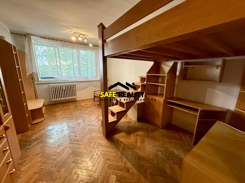 Jednoizbový byt s lodžiou, Žilina - Centrum - Miestnosť v 1-izbovom byte s poschodovou posteľou, drevenými podlahami a nábytkom.