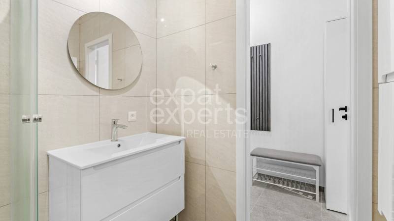 Moderný, zrekonštruovaný 3i byt 68m2, s lodžiou, pivnicou a parkovaním - Kúpeľňa v 3-izbovom byte s okrúhlym zrkadlom a bielym umývadlom.