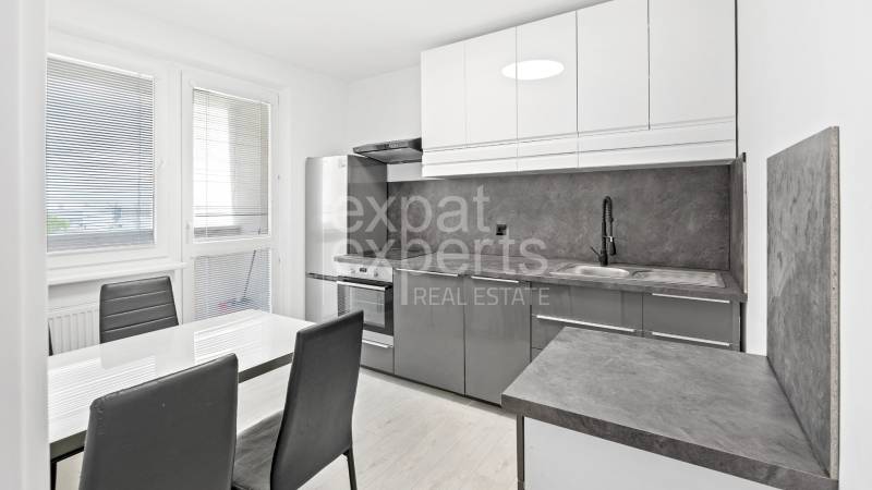 Moderný, zrekonštruovaný 3i byt 68m2, s lodžiou, pivnicou a parkovaním - Kuchyňa v 3-izbovom byte so sivými skrinkami, jedálenským stolom a vstavanými spotrebičmi.
