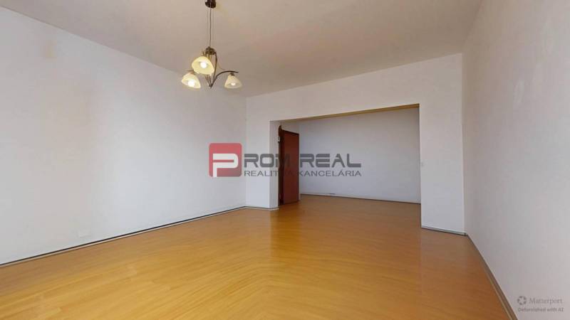 Predaj 3i, 74m2 bytu s výhľadom na Draždiak, Bratislava - Priestranná obývačka s drevenou podlahou a lustrom v 3-izbovom byte.