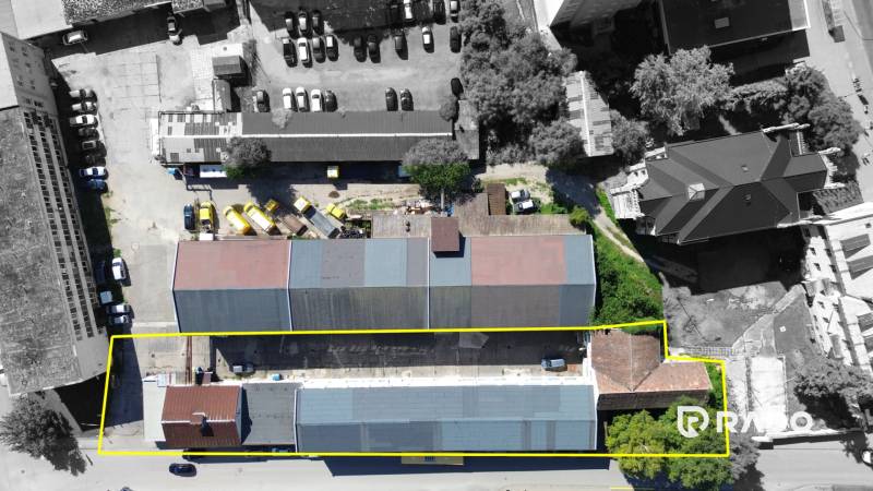 Budova vhodná na developérsky projekt | Vrbové - Budova na ulici SNP vo Vrbovom, obklopená autami a zeleňou.