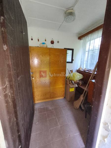 CHATA KORDÍKY - 2 poschodia, 3 izby+kuchynka, kúpelňa - 420 m2 pozemok - Interiér chaty s drevenou skriňou a oknom, vedľa kartónových škatúľ a metly.