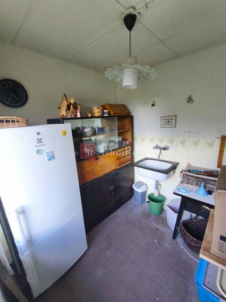 CHATA KORDÍKY - 2 poschodia, 3 izby+kuchynka, kúpelňa - 420 m2 pozemok - Kuchynka v chate s umývadlom, chladničkou, vitrínou a hodinami na stene.