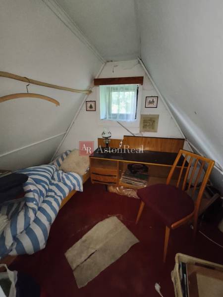 CHATA KORDÍKY - 2 poschodia, 3 izby+kuchynka, kúpelňa - 420 m2 pozemok - Podkrovná izba v chate s posteľou, stolom a stoličkou, biela stena.