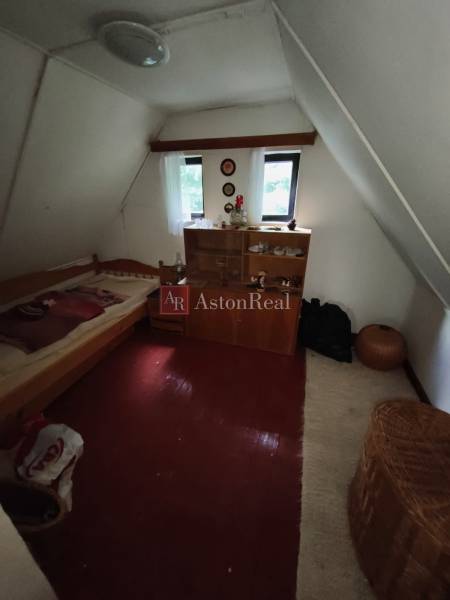 CHATA KORDÍKY - 2 poschodia, 3 izby+kuchynka, kúpelňa - 420 m2 pozemok - Podkrovná izba v chate s posteľou, skrinkou a podlahou s dreveným dekorom.