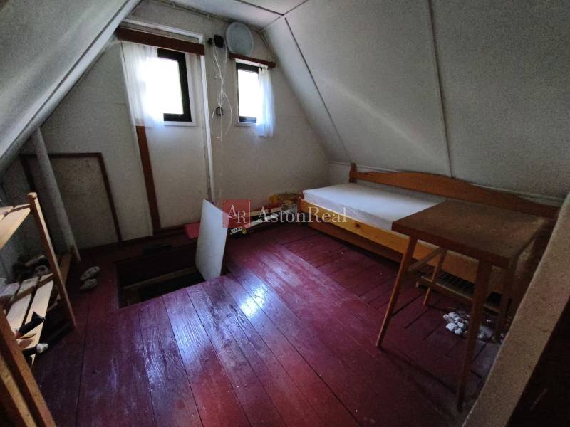 CHATA KORDÍKY - 2 poschodia, 3 izby+kuchynka, kúpelňa - 420 m2 pozemok - Izba na poschodí v chate s podlahou s dreveným dekorom, jednoduchým nábytkom a oknami.