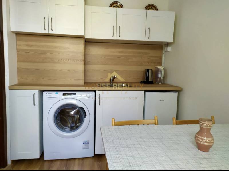 Prenájom pekný 1 izbový byt, Bratislava II. Vrakuňa, Bieloruská ulica - Kuchyňa v 1-izbovom byte s bielymi skrinkami, práčkou, umývadlom a jedálenským stolom.