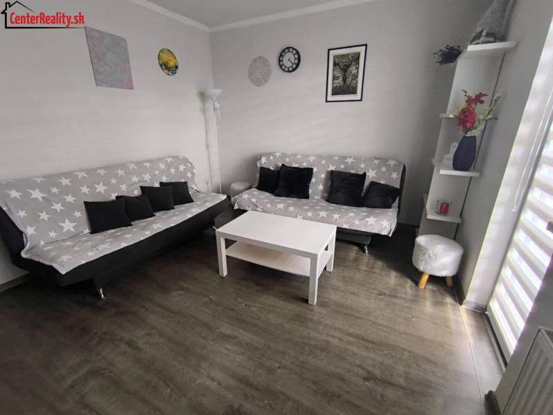 ‼️2 IZBOVÝ BYT NA PRENÁJOM, PARTIZÁNSKE -CENTRUM (KOMPLET ZARIADENÝ)‼️ - Obývacia izba v 2-izbovom byte s dvoma pohovkami, stolíkom a dekoráciami.