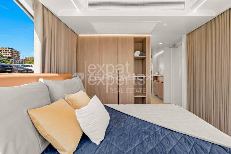 Mobilný dom VESSEL E7 s balkónom, 38 m2 - Spálňa v Zvláštnych nehnuteľnostiach s posteľou, skriňou a výhľadom na exteriér.