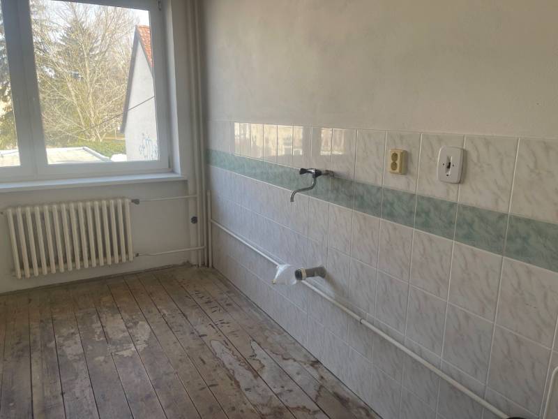 VÝNIMOČNÁ INVESTIČNÁ PRÍLEŽITOSŤ V CENTRE PIEŠŤAN - Prázdna kuchyňa v rodinnom dome s dlaždicami a drevenou podlahou.