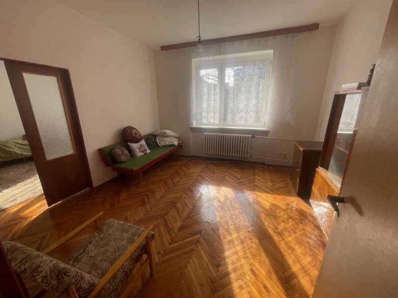 VÝNIMOČNÁ INVESTIČNÁ PRÍLEŽITOSŤ V CENTRE PIEŠŤAN - Drevené parkety v svetlej miestnosti rodinného domu s pohovkou a kreslom.