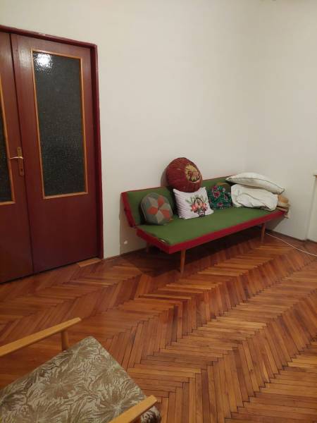 VÝNIMOČNÁ INVESTIČNÁ PRÍLEŽITOSŤ V CENTRE PIEŠŤAN - Interiér rodinného domu s drevenou podlahou, pohovkou a vankúšmi v rohu izby.