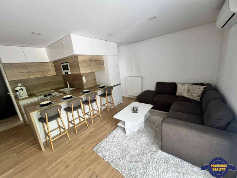 PREDAJ: 3 izbový luxusný byt s balkónom - Komárno - Obývacia izba v 3-izbovom byte s kuchyňou, barovým pultom a rohovou sedačkou.