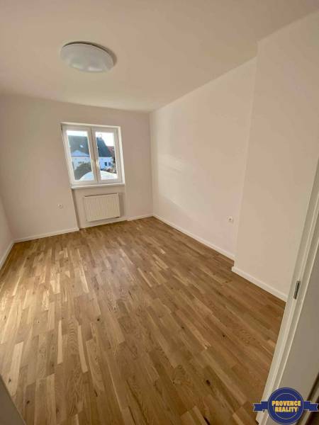 PREDAJ: 3 izbový luxusný byt s balkónom - Komárno - Izba v 3-izbovom byte s drevenou podlahou a bielymi stenami, okno s výhľadom.