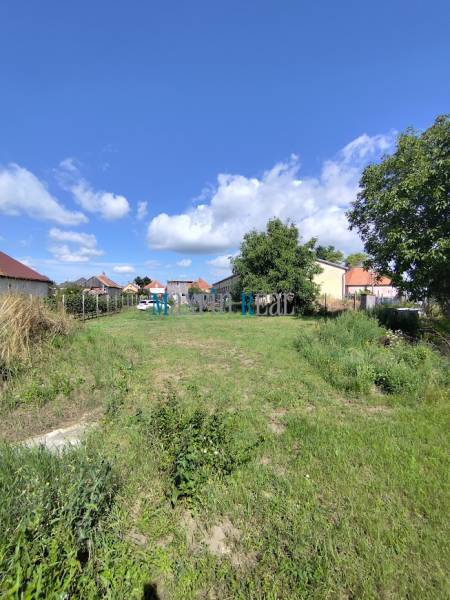  Väčší pozemok s chatkou a murovanou pivnicou - Pozemky - bývanie v Jelšovciach s výhľadom na okolité domy a modrou oblohou.