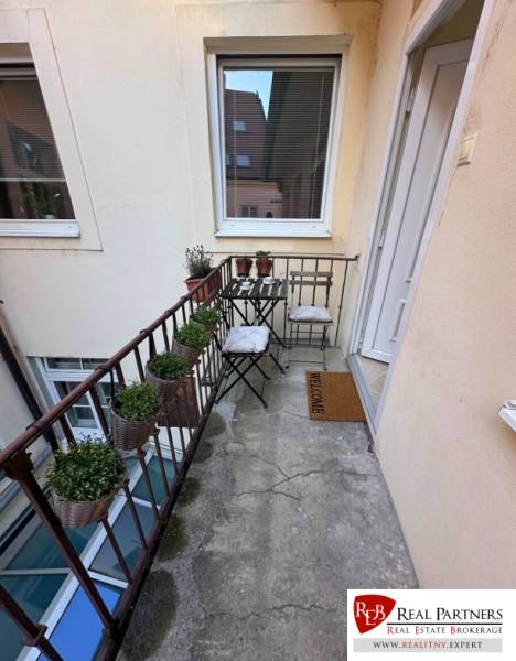Prenájom 2-izb bytu na Ventúrskej ulici, Bratislava- centrum - Balkón vo Ventúrskej v Bratislave pri 2-izbovom byte s rastlinami a stoličkami.