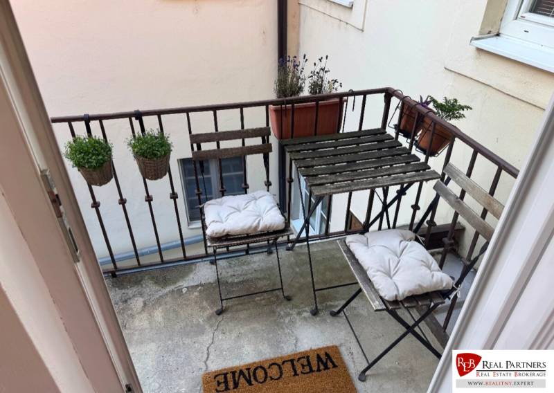 Prenájom 2-izb bytu na Ventúrskej ulici, Bratislava- centrum - Balkón 2-izbového bytu s kovovým nábytkom a kvetináčmi.
