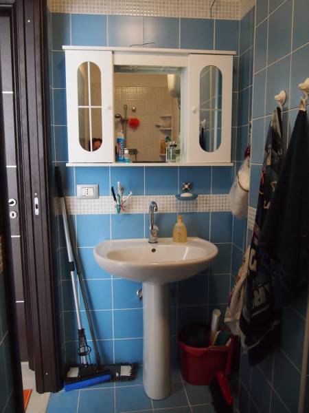 Predaj bytu 3-izbového (3+kk) s rozlohou 65 m² a terasou 10 m², Scalea - Kúpeľňa v 3-izbovom byte s modrými obkladačkami, umývadlom a nástennou skrinkou.