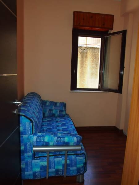Predaj bytu 3-izbového (3+kk) s rozlohou 65 m² a terasou 10 m², Scalea - Modrá pohovka pri otvorenom okne v 3-izbovom byte s drevenou podlahou.