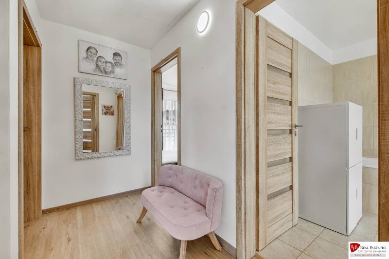 Predaj 4 izbový dom.100 m2, pozemok 208 m2, Štúrova ul, Stupava - Chodba v rodinnom dome s ružovou lavicou, zrkadlom a drevenými dverami.