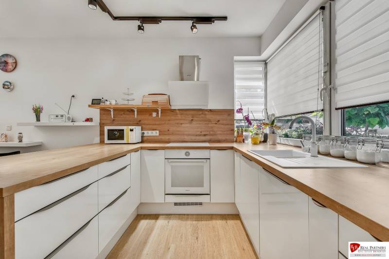 Predaj 4 izbový dom.100 m2, pozemok 208 m2, Štúrova ul, Stupava - Kuchyňa v rodinnom dome so svetlými skrinkami, drevenou pracovnou doskou a veľkými oknami.