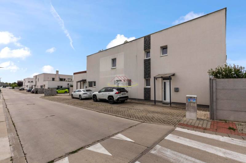 Priestranný 4-izbový byt s  terasou, zariadením, loggiou, 2 x parking - Rovinka, ulica Pivonková, radová zástavba so zaparkovanými autami pred 4-izbovými bytmi.