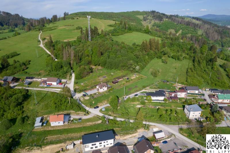 Stavebný pozemok na predaj - Raková - Letecký pohľad na pozemky pre bývanie v Rakovej, obklopené zelenými kopcami a domami.