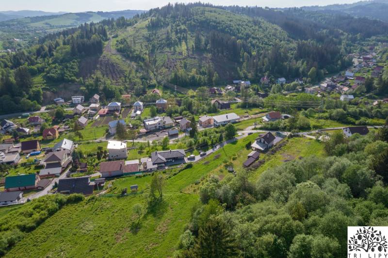 Stavebný pozemok na predaj - Raková - Letecká snímka rakovských pozemkov na bývanie obklopených zeleňou a kopcami.