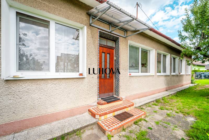 LADCE_Dom na rekonštrukciu podľa vašich predstáv  - Rodinný dom na ulici Pavla Koyša v Ladcoch s bielymi oknami a dverami.