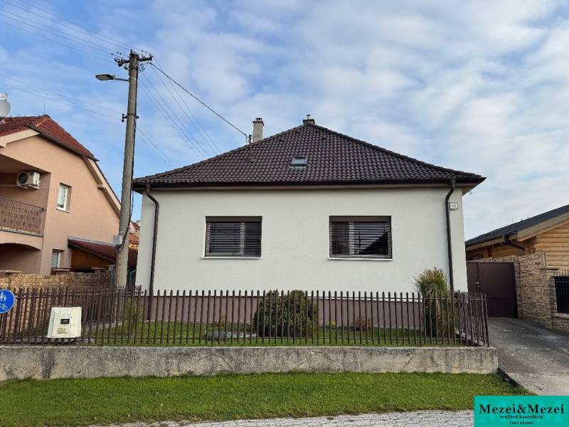 ? Na predaj: Rodinný dom s vedľajšou stavbou – Trstin (okres Trnava) - Rodinný dom v Trstíne so šikmou strechou, oplotenie a trávnatá plocha pred domom.