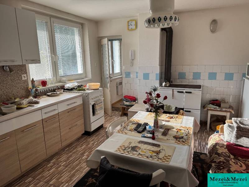 ? Na predaj: Rodinný dom s vedľajšou stavbou – Trstin (okres Trnava) - Kuchyňa v rodinnom dome s klasickým nábytkom, stolom a pecou.