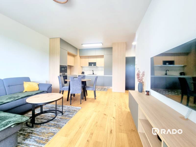 | EXKLUZÍVNE! | Krásny NOVÝ 2-izbový byt | 48m² | Čerešne - Obývacia izba v 2-izbovom byte s kuchyňou, jedálenským stolom a pohovkou.