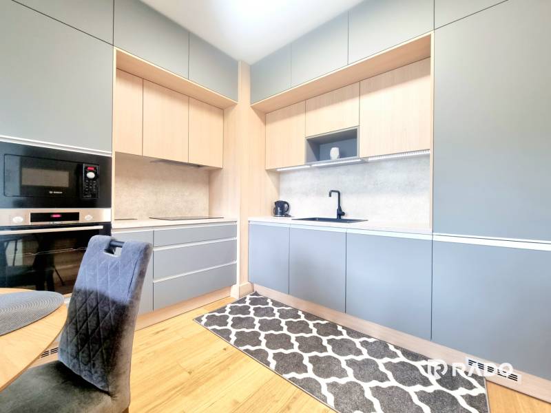 | EXKLUZÍVNE! | Krásny NOVÝ 2-izbový byt | 48m² | Čerešne - Kuchyňa v 2-izbovom byte s elegantnými sivými a drevenými skrinkami, čiernym spotrebičom a koberec.