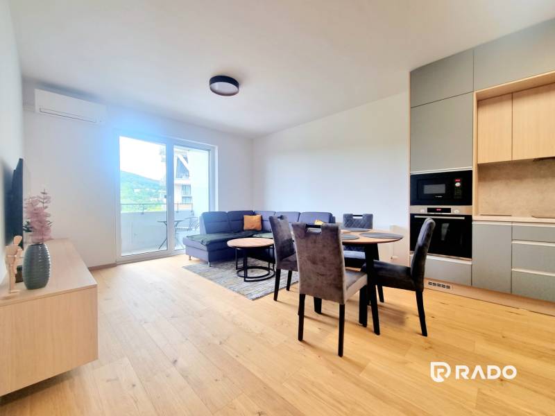 | EXKLUZÍVNE! | Krásny NOVÝ 2-izbový byt | 48m² | Čerešne - Obývacia izba v 2-izbovom byte s pohovkou, stolom a kuchyňou.