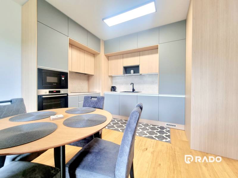 | EXKLUZÍVNE! | Krásny NOVÝ 2-izbový byt | 48m² | Čerešne - Kuchyňa s jedálenským stolom v 2-izbovom byte, vybavená spotrebičmi a drevenými skrinkami.