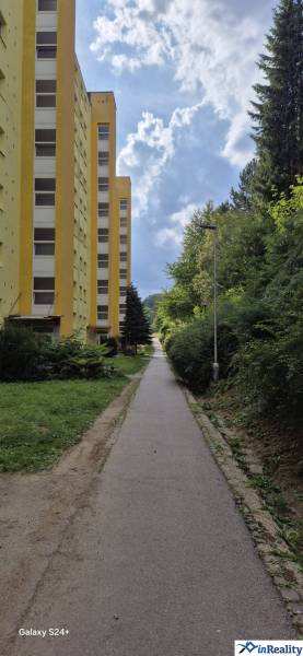 3i byt ul. Moskovská, Banská Bystrica - Žltý bytový dom na Moskovskej ulici v Banskej Bystrici vedľa chodníka a zelene.