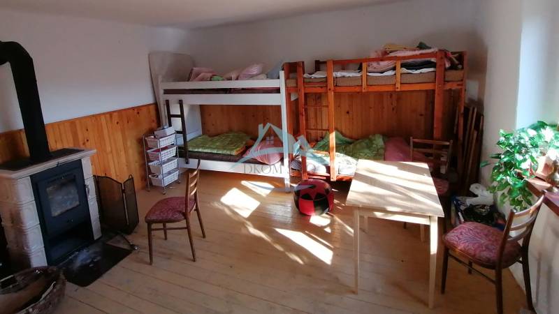 Dva malebné vidiecke domy na rozľahlom pozemku (1,6ha) v osade Prieloh - Poschodové postele, krbové kachle a nábytok v miestnosti v rodinnom dome.