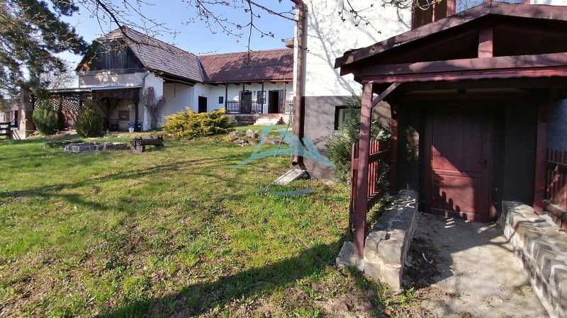 Dva malebné vidiecke domy na rozľahlom pozemku (1,6ha) v osade Prieloh - Záhrada, rodinný dom, posedenie, trávnatá plocha, drevený prístrešok, slnečné osvetlenie.