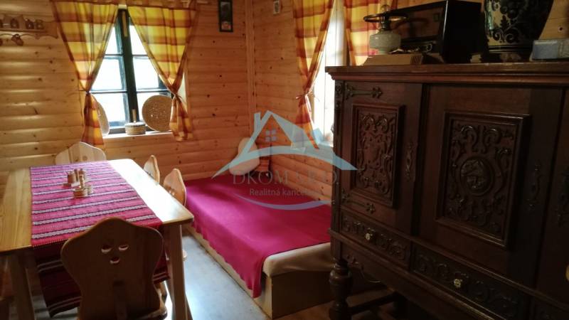 Dva malebné vidiecke domy na rozľahlom pozemku (1,6ha) v osade Prieloh - Interiér drevenice s masívnym nábytkom, drevenými stenami a farebnými závesmi v rodinnom dome.