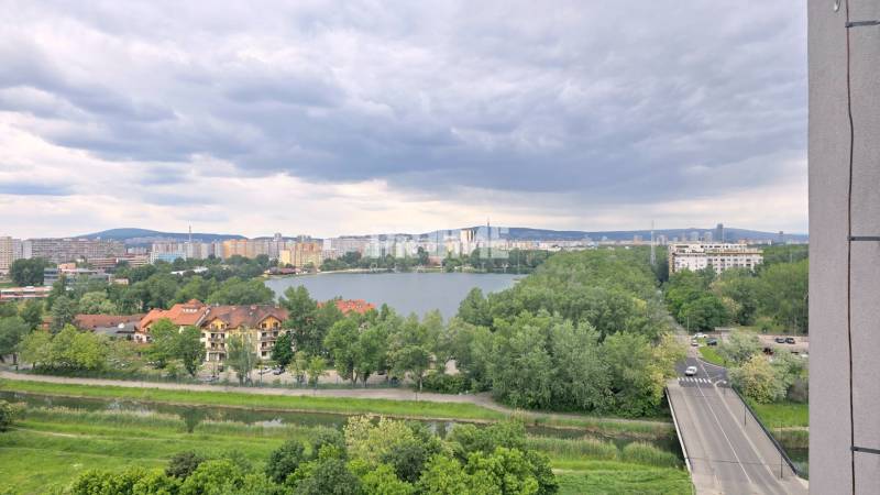 Predaj 3i byt, nepriechodné izby, výhľad, jazero Dražiak, Petržalka - Výhľad na jazero a Bratislavu-Petržalku z Krásnohorskej ulice, obkolesený zeleňou a budovami.
