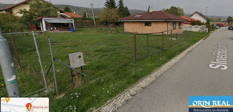 PREDAJ SP V ČASTEJ - 691 m2  ,,, ZNÍŽENÁ CENA,,, - Na ulici Slnečná pozemky: Trávnik, dom, oplotenie, budovy a stromy v pozadí.