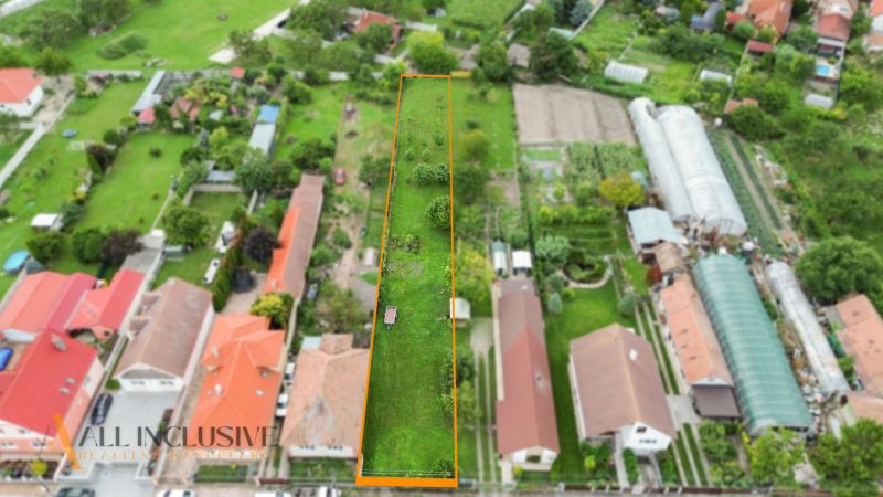 NA PREDAJ STAVEBNÝ POZEMOK - 1266 m², ROHOVCE - Letecký pohľad na úzky pozemok na bývanie v Rohovciach, ohraničený budovami a záhradami.