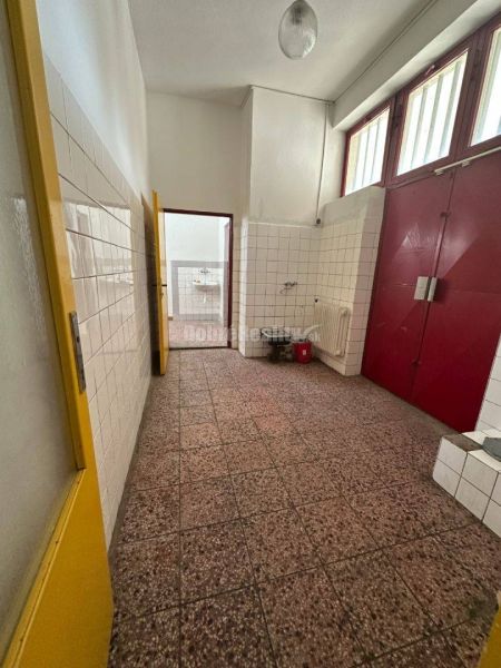 Dobré reality - Polyfunkčný objekt na predaj - Interiér budovy s dlažbou, bielymi dlaždicami, červenými dverami a umývadlom.