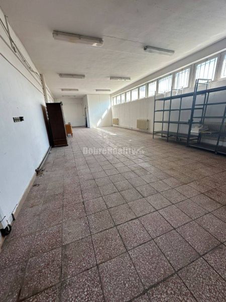 Dobré reality - Polyfunkčný objekt na predaj - Prázdna miestnosť v budove s dlažbou, policami a veľkými oknami.